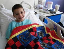 A happy recipient of a hand-crafted quilt delivered by a Quilts for Kids volunteer.
