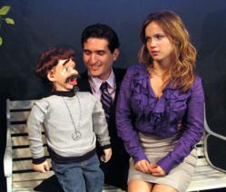 Scene from the new musical comedy, The Capitalist Ventriloquist, showing the heir to a hedge fund, Alan, who would rather be a singing ventriloquist, with ambitious dummy, Randy, and his fiance', Branda, who isn't sure she wants to be married to a ventril