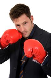 Businessman in suit wearing boxing gloves and fighting wrinkles with Knockout skincare for men.