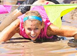 Woman smiling and crawling through the Mud bath.