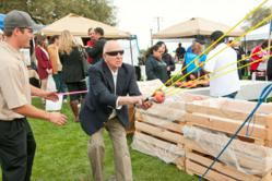 Photo by Nancy Robbins: Brian Davis of Twin Pomegranates Winery looks on as a festival-goer attempts a shot on the popular Pomegranate Grenade launcher at last year's Pomegranate Festival