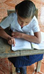 Priscella reads from one of the school's textbooks. It's her turn to take home a book that is shared by the other students in her grade.