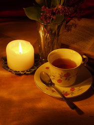 A tea cup warmly lit by a candle.