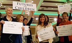 Futures for Children President/CEO, Teresa C. Gomez (holding FFC sign) surrounded by supporters displaying their $500 grant checks.