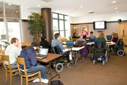 A classroom filled with people in wheelchairs and assistive devices being instructed by Lynn Wehrman