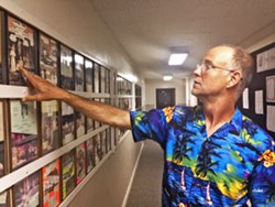 Don Hooper points to past playbills in the Marjorie Lyons Playhouse