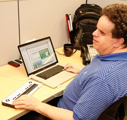 Man using Braille EDGE 40 at work with a laptop