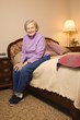 Female senior citizen sitting on bed