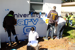 Students and instructors from UACDC's Prodigy cultural arts program paint the mural on the Harvest Hope Center.