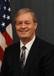 Photo of Lowell Pimley, Acting Commissioner of Bureau of Reclamation. He is standing in front of an American Flag.