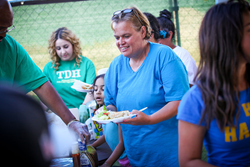 Drug and alcohol addiction treatment center employees provide and serve meal for homeless families.