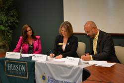 Taking part in the signing event are, from left, Jen Flynn, Husson’s Presque Isle Campus Director; Dr. Marie Hansen, Husson’s College of Business Dean; and Dr. Ray Rice, UMPI’s Provost.