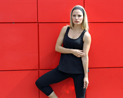 Model Jill Billingsley is wearing a solid black TerraFrog Swing Tennis Tank paired with black and grey yoga pants