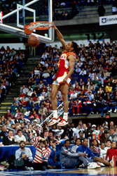Picture shows Spud Webb slam dunking in front of a crowd.