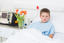 Shows young boy sitting in hospital bed.