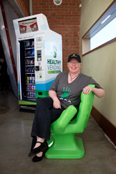 Pinky Harris, a Licensed Randolph-Sheppard Vendor, sits in front of a HUMAN Healthy Vending machine.
