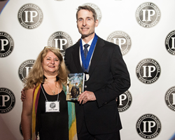 S. Chris Shirley, author of Playing by the Book, and his publisher, Lori Perkins, pose for a press photo after winning a National Medal in Religious Fiction at the 19th Annual IPPY Awards in New York City