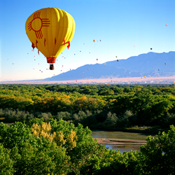 The New Mexico Zia sun symbol (State Flag) balloon over the Rio Grande Valley. Photo by MarbleStreetStudio.com