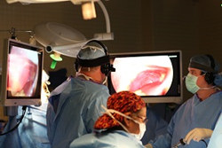 Dr S. Brooks (left), "expert" surgeon and Dr. A. Purtell (right), resident "novice" surgeon, wearing paired EyeGuides, look on their respective monitors while doing surgery.