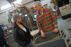 Andrea Garcia (left) tours the Denver-based Coda Coffee Company warehouse with co-founder Tommy Thwaites (right). Coda Coffee Company is the coffee roaster and supplier for Ziggi's Coffee.