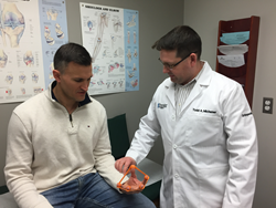 Dr. Todd Michener teaching a patient how to rehabilitate his tennis elbow with Hand X Band.