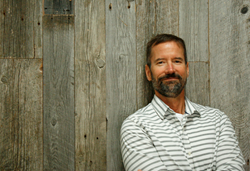 Tim Roberts, the California and Nevada Reclaimed Wood Expert for Pioneer Millworks poses with reclaimed siding.