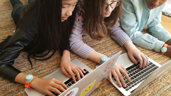 Girls writing code for their Jewelbots Bracelets