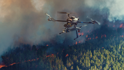 A small UAV is shown surveying the movement of a forest fire.