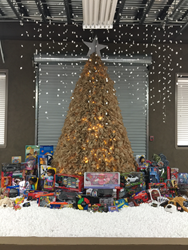 8-foot tall cardboard Christmas tree at Ameritex Movers. Underneath sit toy donations for Mahanay Elementary School