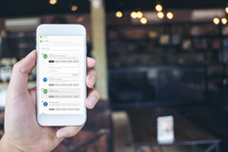 Hand holding smartphone with OneView platform open.
