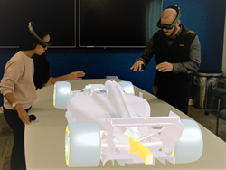 Onshape technical service engineers Gaby Rochino (left) and Tim Fries examine a 3D CAD model of a Formula One race car through the lens of the Magic Leap One spatial computing headset, which enables digital content to step out of the screen and into the real world.