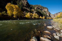 Photo shows the Colorado River flanked by fall colors east of Glenwood Springs, Colorado. Autumn