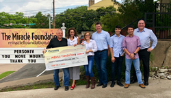 Group standing in front of large check.