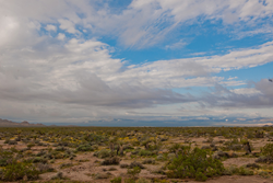 A desert landscape with clouds in a blue sky.