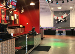 a formula 1 car hangs on a wall in the background of the lobby at k1 speed bend