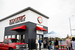 A line of people in front of a Scooter's Coffee location.