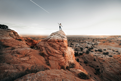 Woman stands on top of natural rock formations in Page, Arizona, admiring the desert. Photo Credit: Ashley Scott