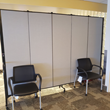 Gray room divider with two chairs in front of it at a vaccination clinic.
