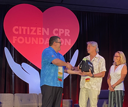 Rob Hoadley, ZOLL Medical, presents an AED to Al and Trish Hart, who accepted the People Saving People Award on behalf of Juliana and Bill Schirmer