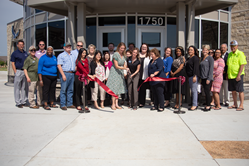 Large group of people celebrating the opening of a new Neighborhood Credit Union branch in Waxahachie by cutting a large ribbon. 