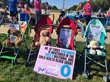 Four empty strollers with teddy bears and memorial signs and a demonstration sign.