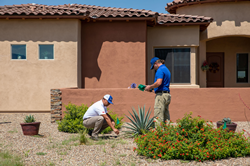 The owner of Conserva Irrigation of Tucson East and one of their technicians work on a drip irrigation system.
