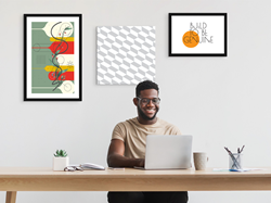 Canvas prints on the wall behind a person seated at the desk
