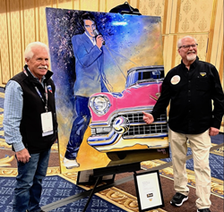 Wayne Carini, host of the Chasing Classic Cars TV Series , and artist Kelly Telfer pose next to Telfer’s original fine art painting: Elvis and His Cars at the official unveiling during SEMA 2022