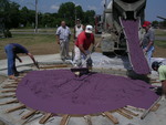 Workers spread specially-dyed concrete provided by The QUIKRETEÂ® Companies into the purple heart mold.
