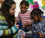A student from Conrad Ball Middle school reads to two children from Denver Great Kids Head Start.