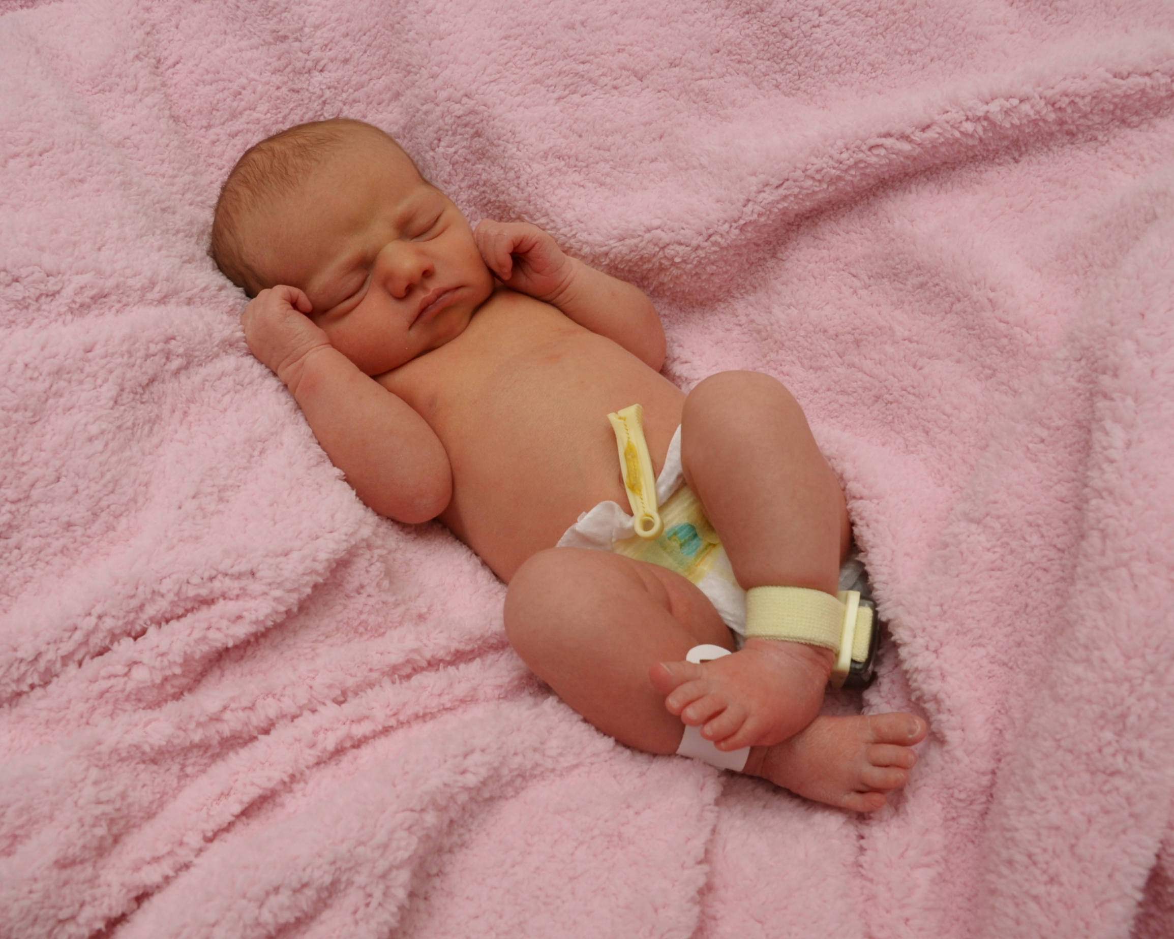 A newborn infant wearing an Accutech "Cuddles" tag.