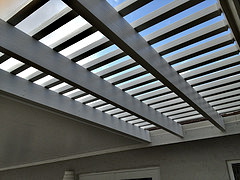 A wood-look aluminum pergola and insulated roof combination installed by Venetian Builders, Inc., Miami. The pergola provides shade but promotes ventilation.