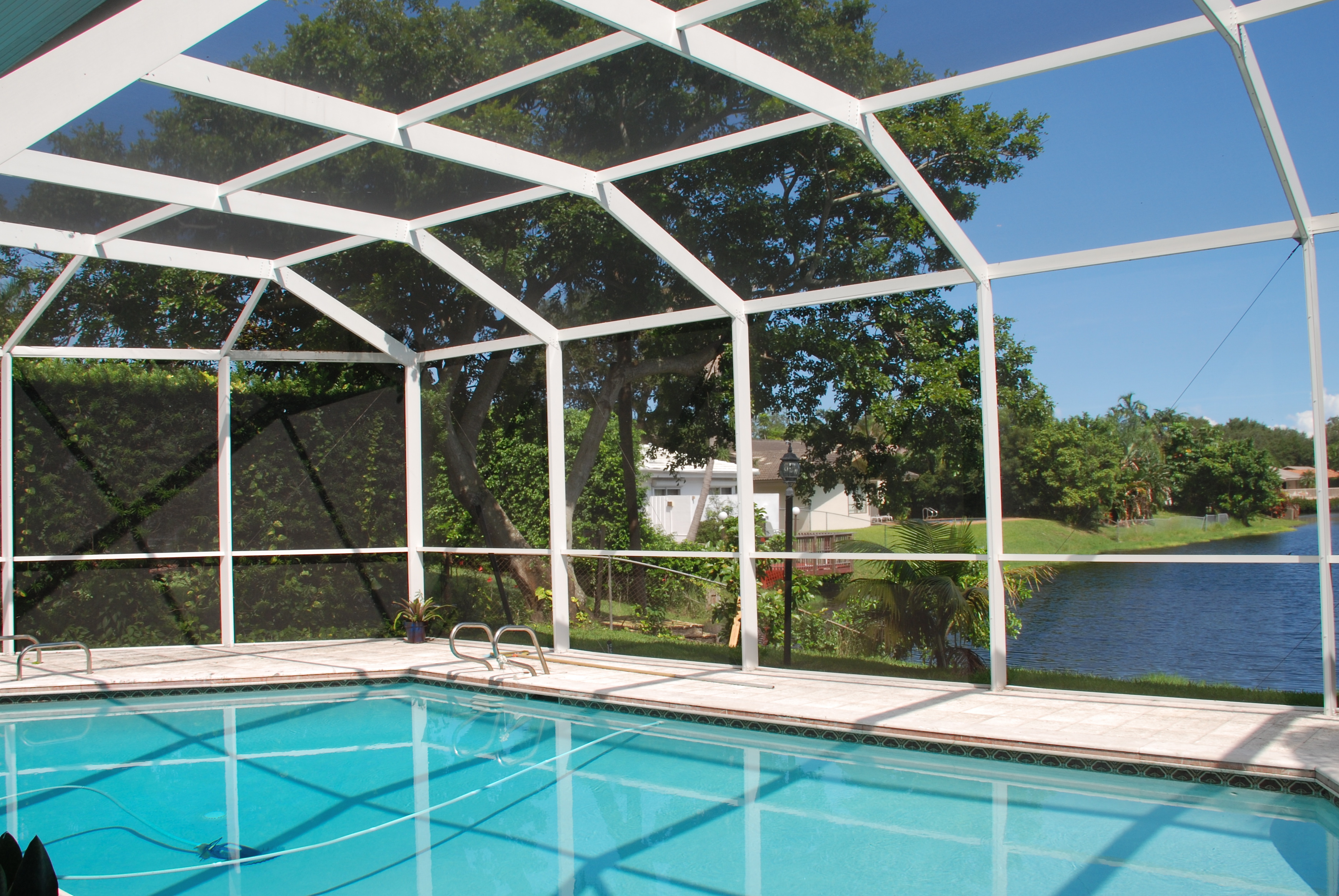 A screen pool enclosure from Venetian Builders, Inc., Miami. Heavier-gauge framing retains its delicate look but discreetly adds strength against storms and preserves views.