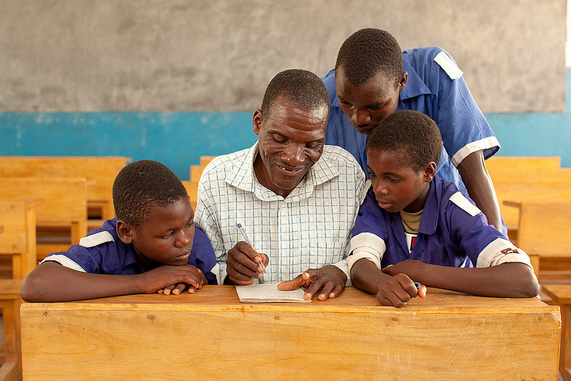 A father and his children attend class in a schoolhouse constructed by buildOn in Malawi.